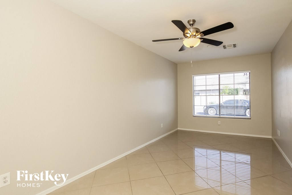 an empty living room with a ceiling fan and a window