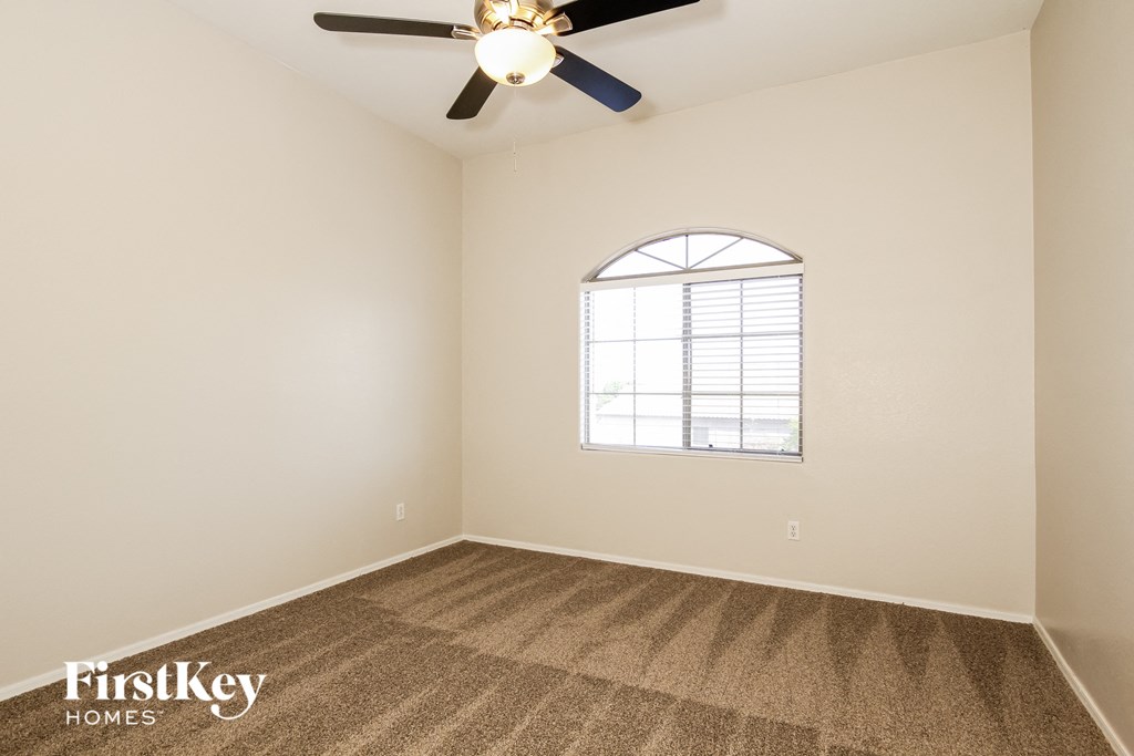 the spacious living room with carpeting and a ceiling fan