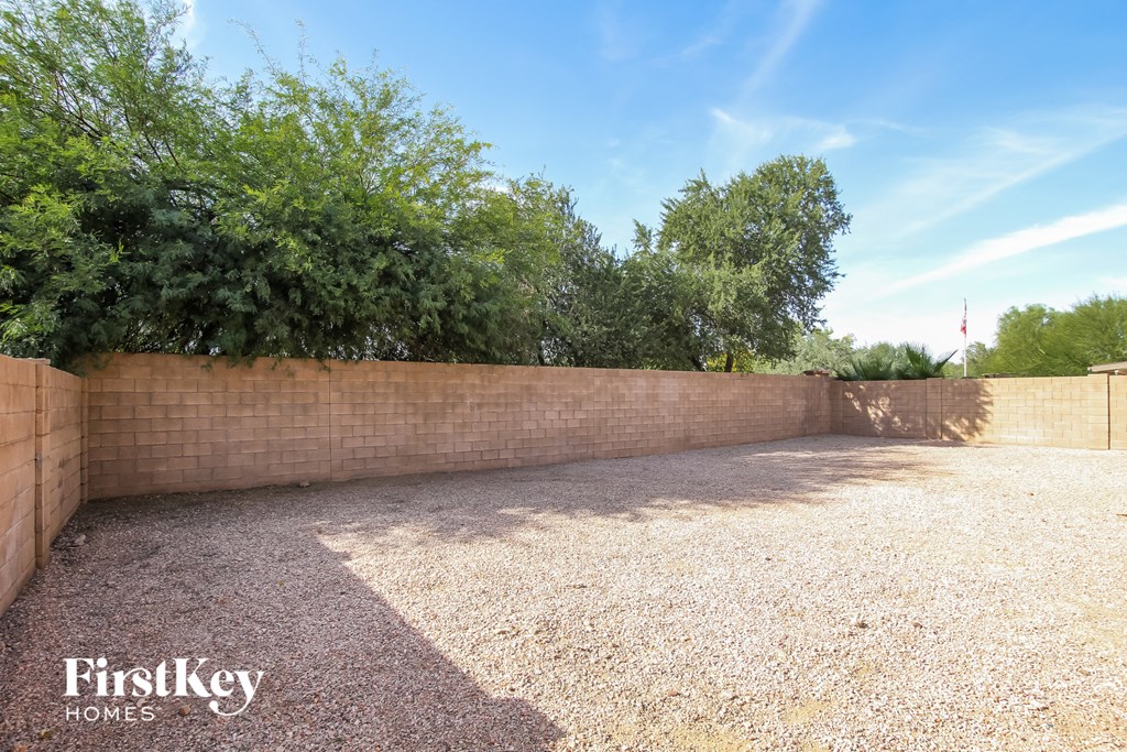 a backyard with a brick retaining wall and trees