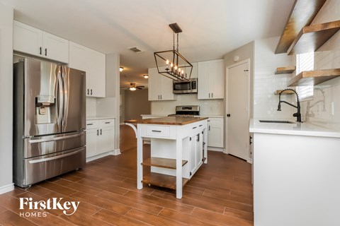 A kitchen with a stainless steel refrigerator and wooden floors.