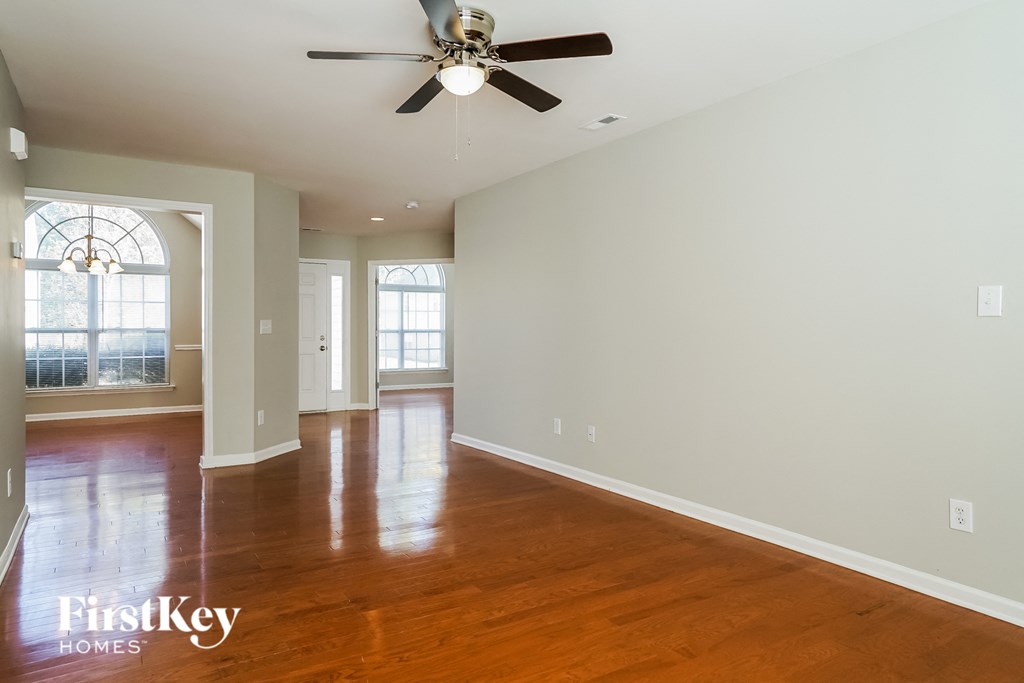 an empty living room with wood floors and a ceiling fan