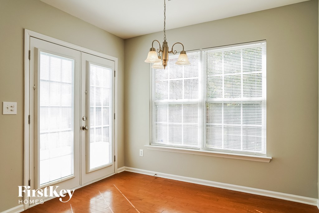a living room with large windows and a door and a chandelier
