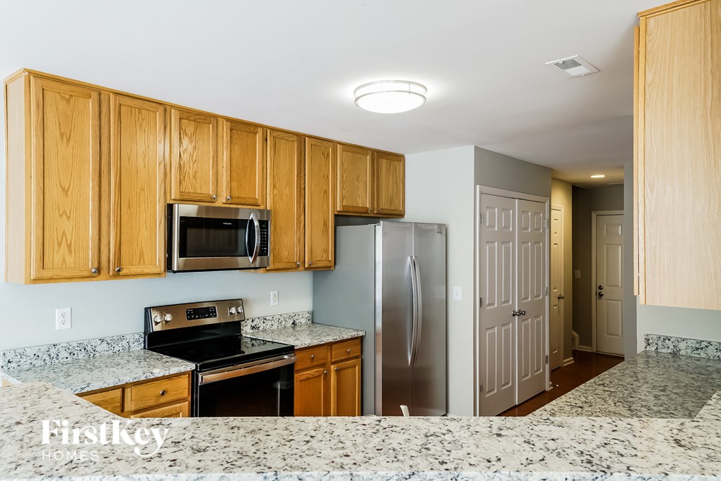 a kitchen with granite counter tops and wooden cabinets and a stainless steel refrigerator
