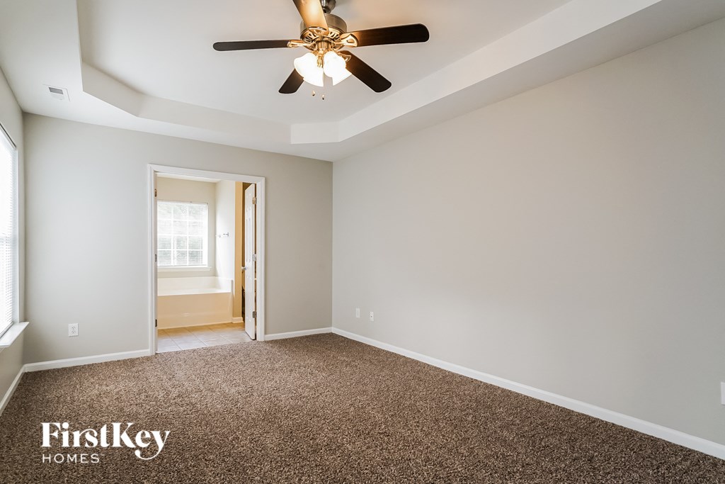 a empty room with a ceiling fan and a carpet