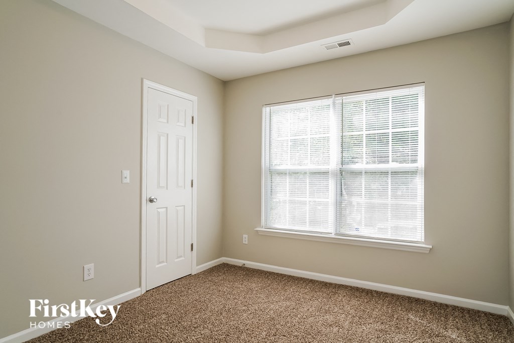 a bedroom with a white door and a window and a carpeted floor