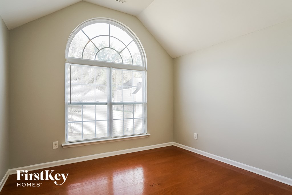 an empty room with a large window and wooden floors