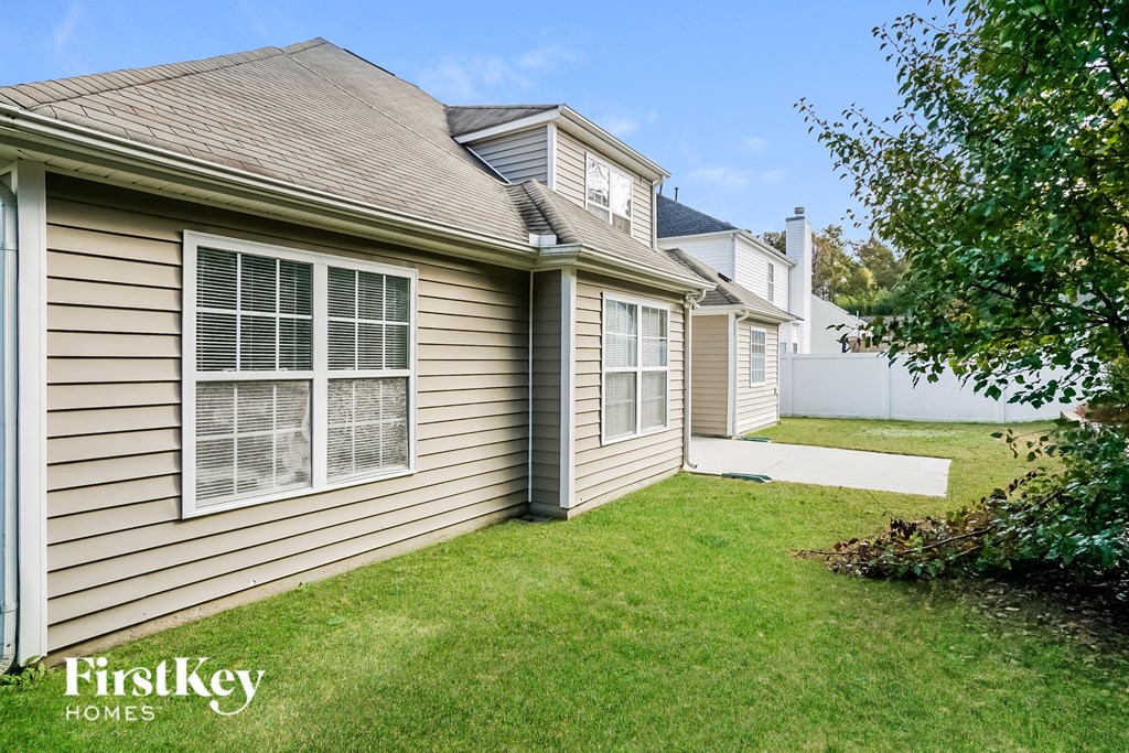 a side view of a house with a yard and a sidewalk