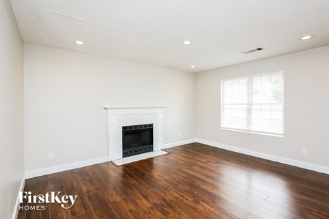 a living room with white walls and a fireplace and wooden floors