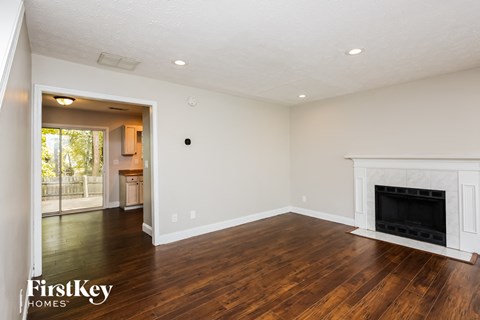 a living room with white walls and a fireplace and wooden floors