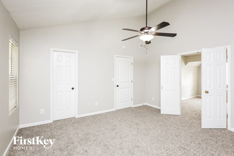 an empty bedroom with a ceiling fan and white doors