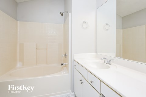a white bathroom with a tub and a sink and a mirror