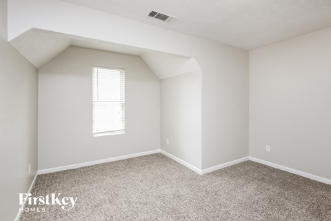 a bedroom with white walls and carpet and a window