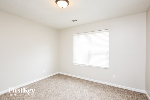 a bedroom with a window and a carpeted floor