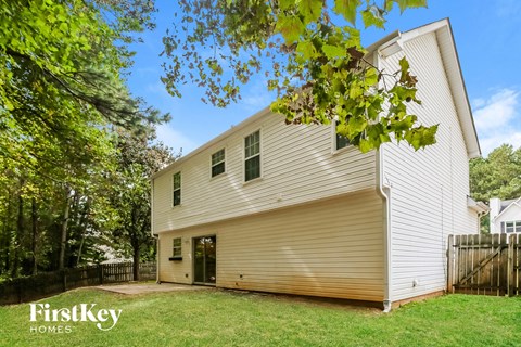 the back of a white house with a yard and trees
