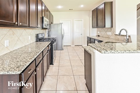a large kitchen with granite counter tops and stainless steel appliances