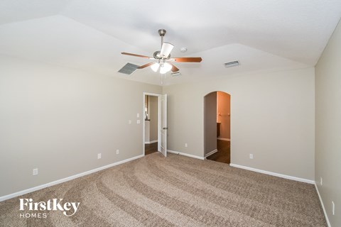 a spacious living room with carpet and a ceiling fan