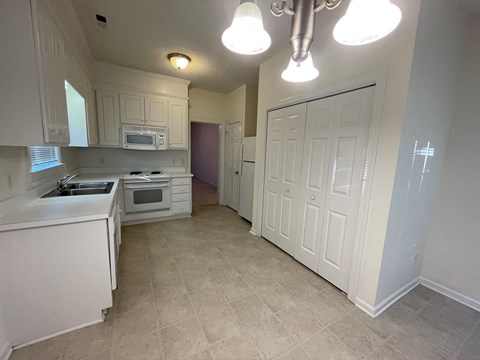 A kitchen with white cabinets and a tiled floor.