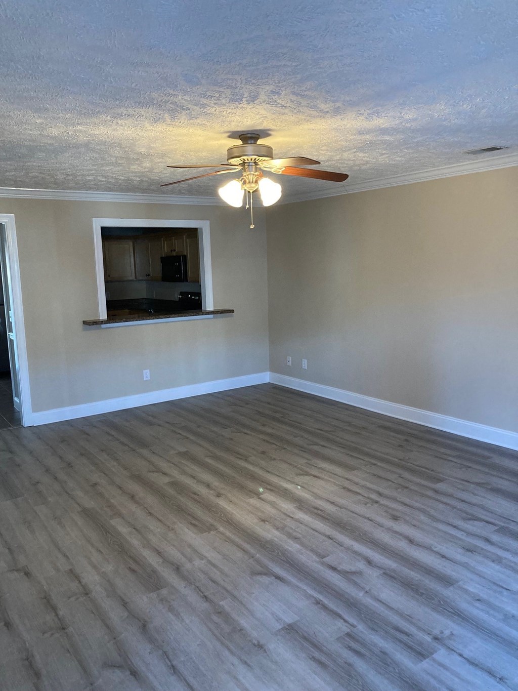an empty living room with wood floors and a ceiling fan