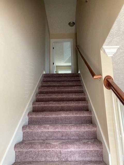 a staircase with carpeted stairs leading up to a door