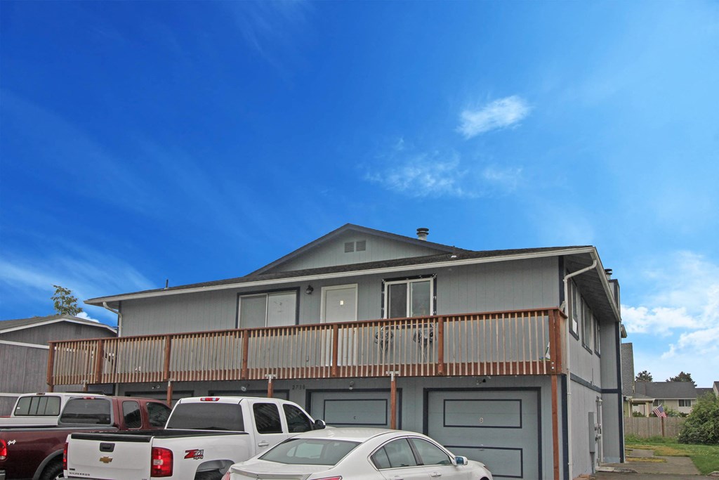 the front of a house with a parking lot full of cars