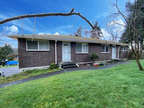 the front of a brick house with a tree branch in the foreground