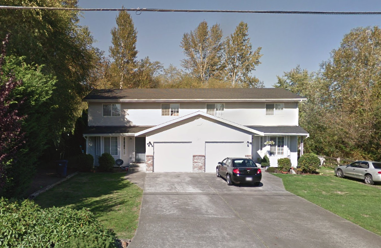 a white house with a car parked in the driveway