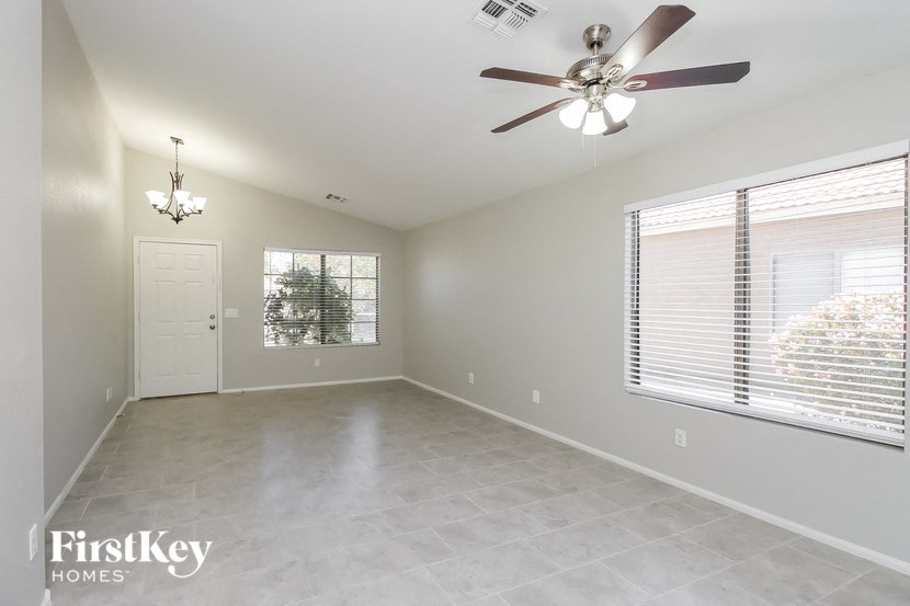 A spacious room with a ceiling fan and a chandelier.