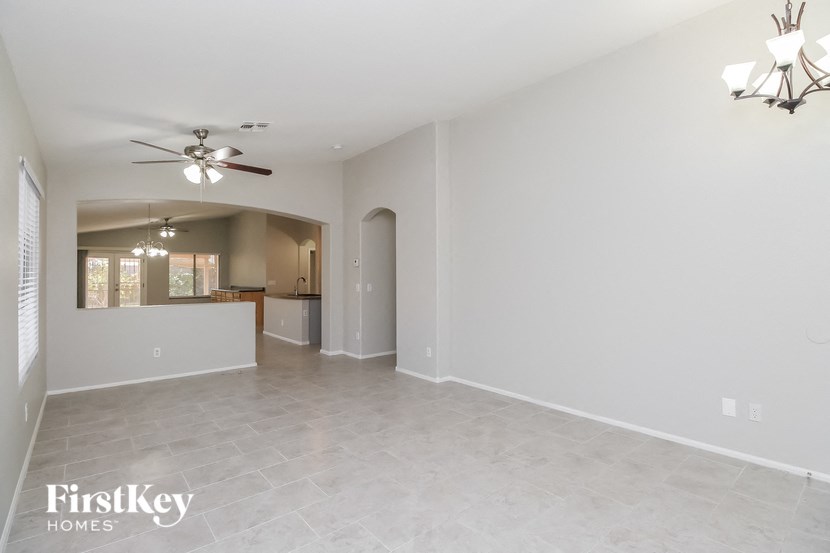 A spacious empty room with a ceiling fan and a chandelier.