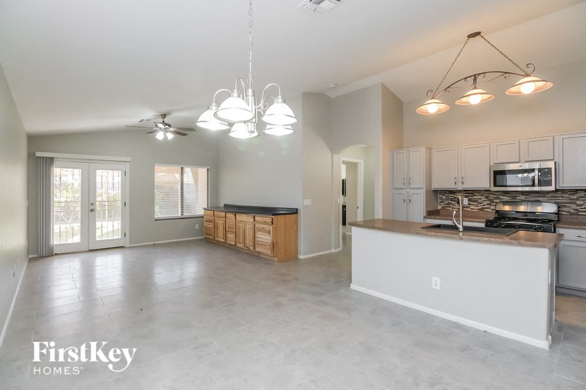 A spacious kitchen and living room with a ceiling fan and pendant lights.
