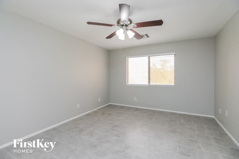 A room with a ceiling fan and a window with blinds.
