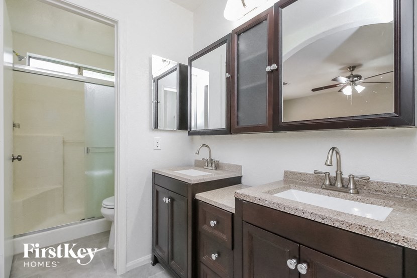 A bathroom with a sink, mirror, and a shower.