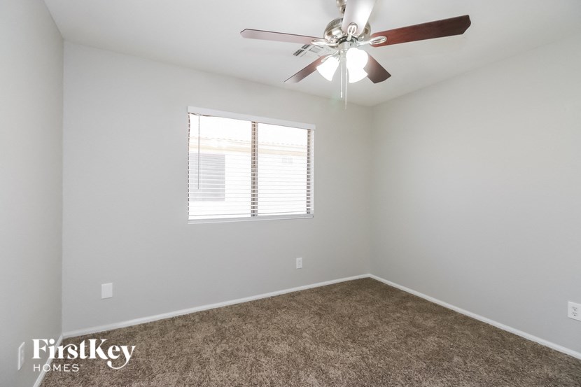 A room with a ceiling fan and a window with blinds.