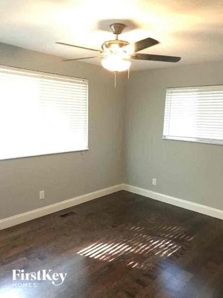 A room with a ceiling fan and two windows.
