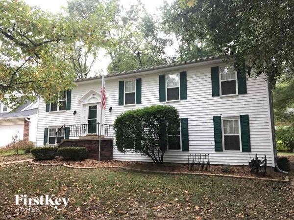 A white house with green shutters and a flag on the front.
