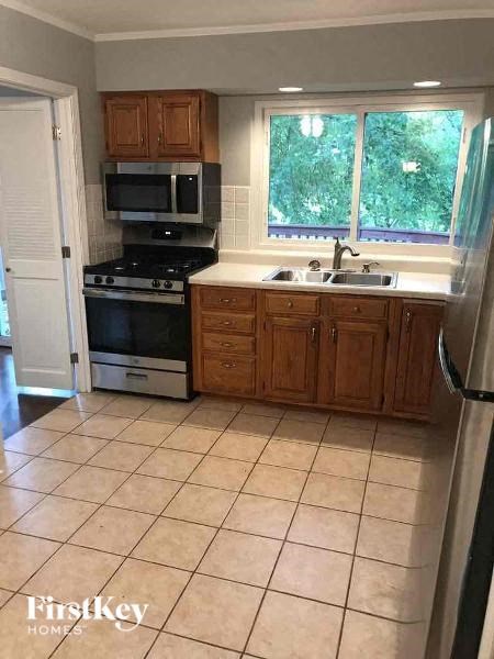 A kitchen with a black stove top oven and a black microwave above it.