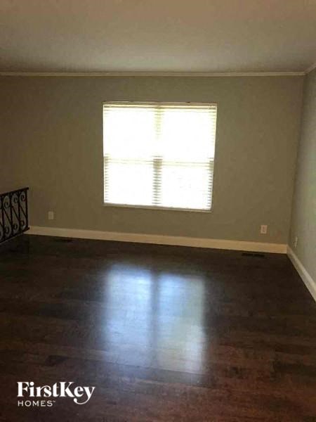 A room with wooden floors and a window with blinds.