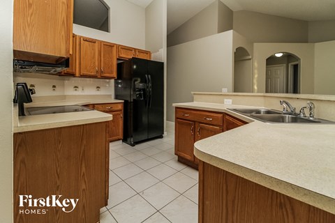 A kitchen with wooden cabinets and a black refrigerator.