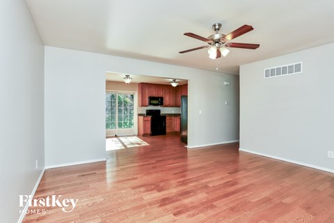 an empty living room with wood flooring and a ceiling fan
