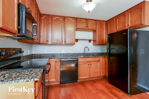 a kitchen with wood cabinets and black appliances and granite counter tops