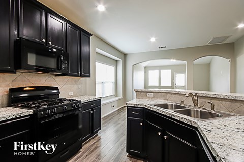 A kitchen with black cabinets and a black stove top oven.