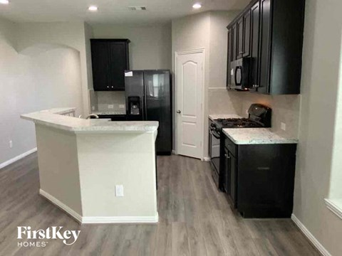 A kitchen with a white counter and black cabinets.