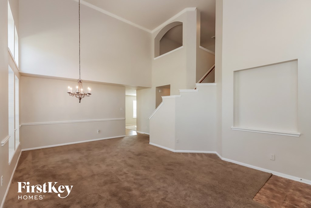 a living room with a carpeted floor and a staircase