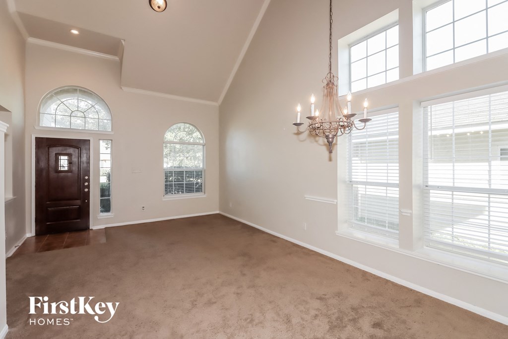 an empty dining room with large windows and a chandelier