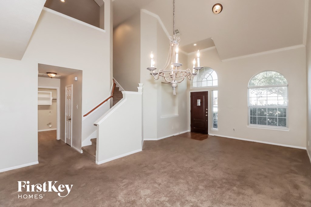 an empty living room with a staircase and a chandelier