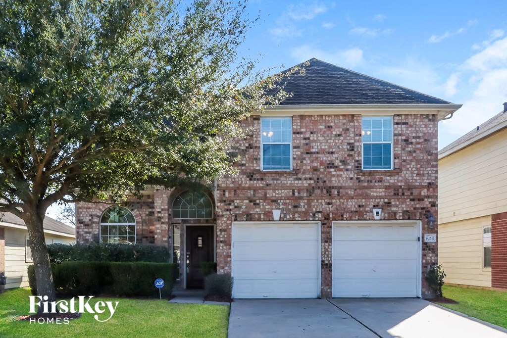 the front of a brick house with two white garage doors