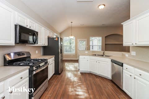 a kitchen with white cabinets and stainless steel appliances and wood floors