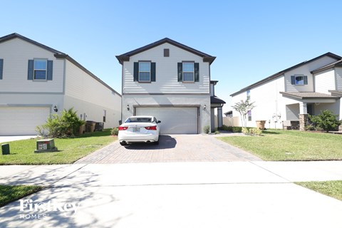 a white car parked in a driveway in front of a house