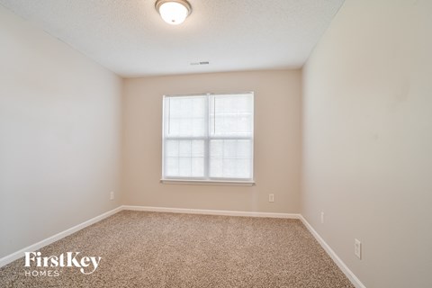 a spacious room with carpet and a window