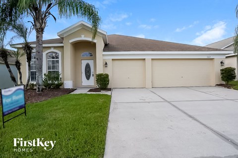a beige house with a driveway and a palm tree