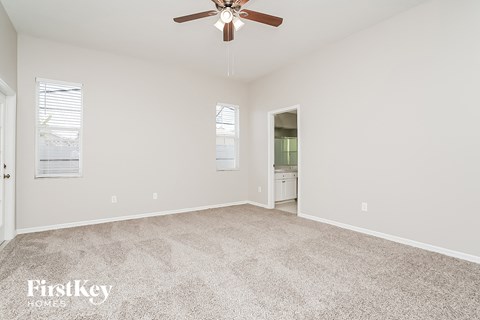 a spacious living room with carpet and a ceiling fan
